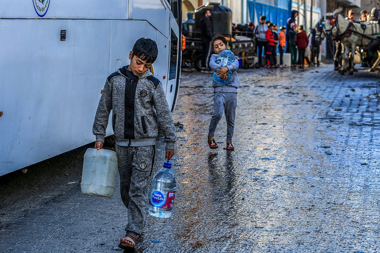 Palestinian children collect drinking water from the UNRWA headquarters in Rafah, southern Gaza Strip, January 29, 2024. (Abed Rahim Khatib/Flash90)