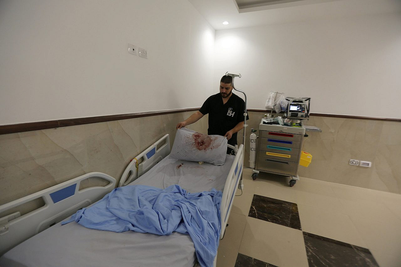 A Palestinian nurse stands next to a hospital bed and pillow covered in blood following an Israeli military operation at the Ibn Sina Hospital, in the occupied West Bank city of Jenin, January 30, 2024. (Nasser Ishtayeh/Flash90)