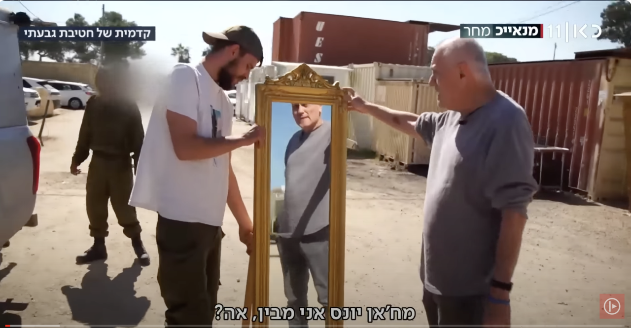 Israeli soldiers display a mirror they stole from Gaza on Israel's public broadcaster, Kan. (Screenshot)