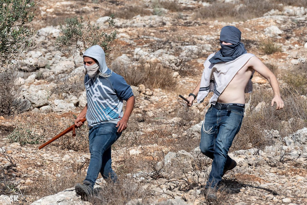 Einan Tanjil (left) and another settler attack Palestinian farmers and Israeli activists in Surif, occupied West Bank. (Shay Kendler)