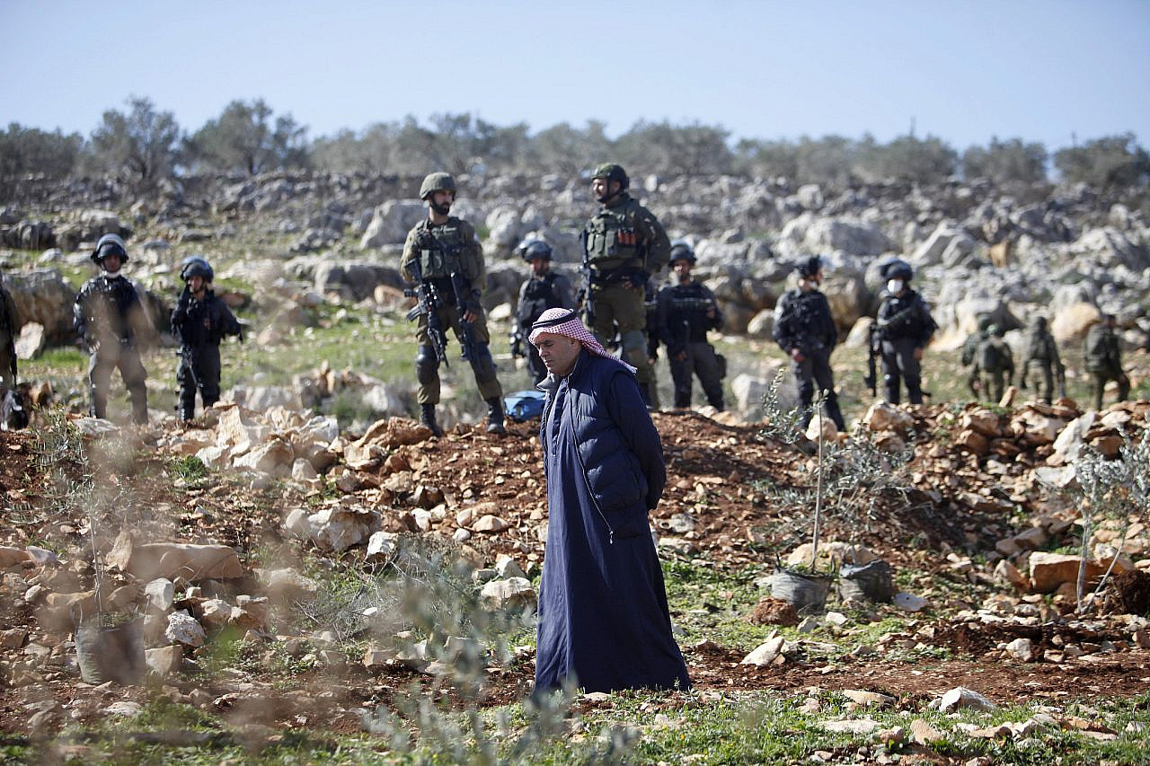 Israeli soldiers are seen behind Palestinians farmers between the settlement of Ariel and the town of Salfit in the northern West Bank, February 3, 2022. (Nasser Ishtayeh/Flash90)