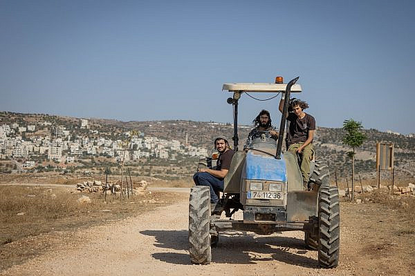 Israeli settlers drive a tractor in the outpost of Ramat Migron, occupied West Bank, September 8, 2023. (Chaim Goldberg/Flash90)