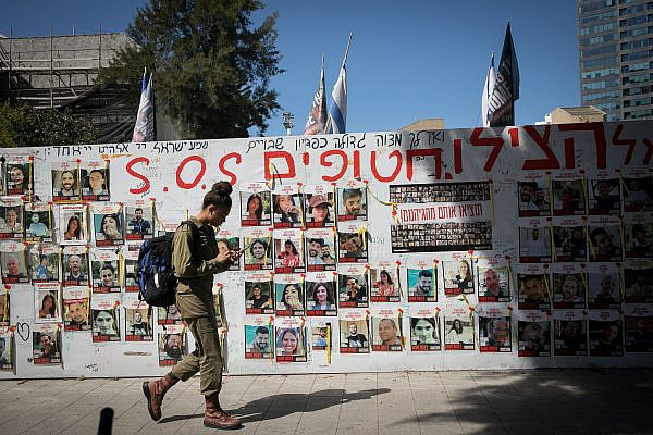 An Israeli soldier walks past a wall of photographs of Israelis still held hostage in Gaza, at "Hostage Square" in Tel Aviv, March 10, 2024. (Miriam Alster/FLASH90)