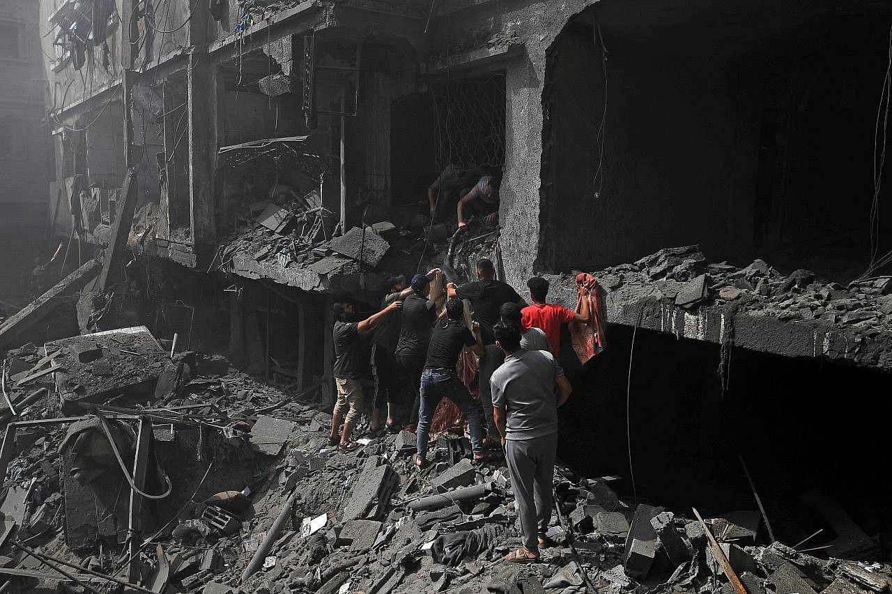 Los palestinos intentan rescatar a los supervivientes y sacar cuerpos de los escombros después de que los ataques aéreos israelíes alcanzaran edificios cerca del Hospital de los Mártires de Al-Aqsa en Deir al-Balah, en el centro de Gaza, el 22 de octubre de 2023. (Mohammed Zaanoun)