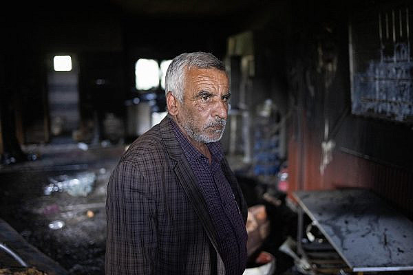 Hussein Dawabsheh, head of the Duma town council, inside a burned house in the town, occupied West Bank, April 14, 2024. (Oren Ziv)