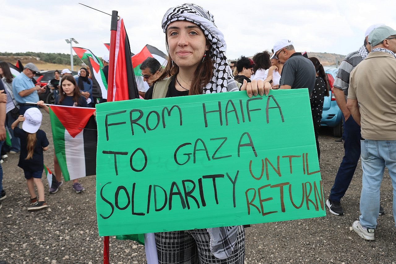 A protester holds a sign at the March of Return in the depopulated villages of Hawsha and Al-Kasair, northern Israel, May 14, 2024. (Ahmad Al-Bazz)
