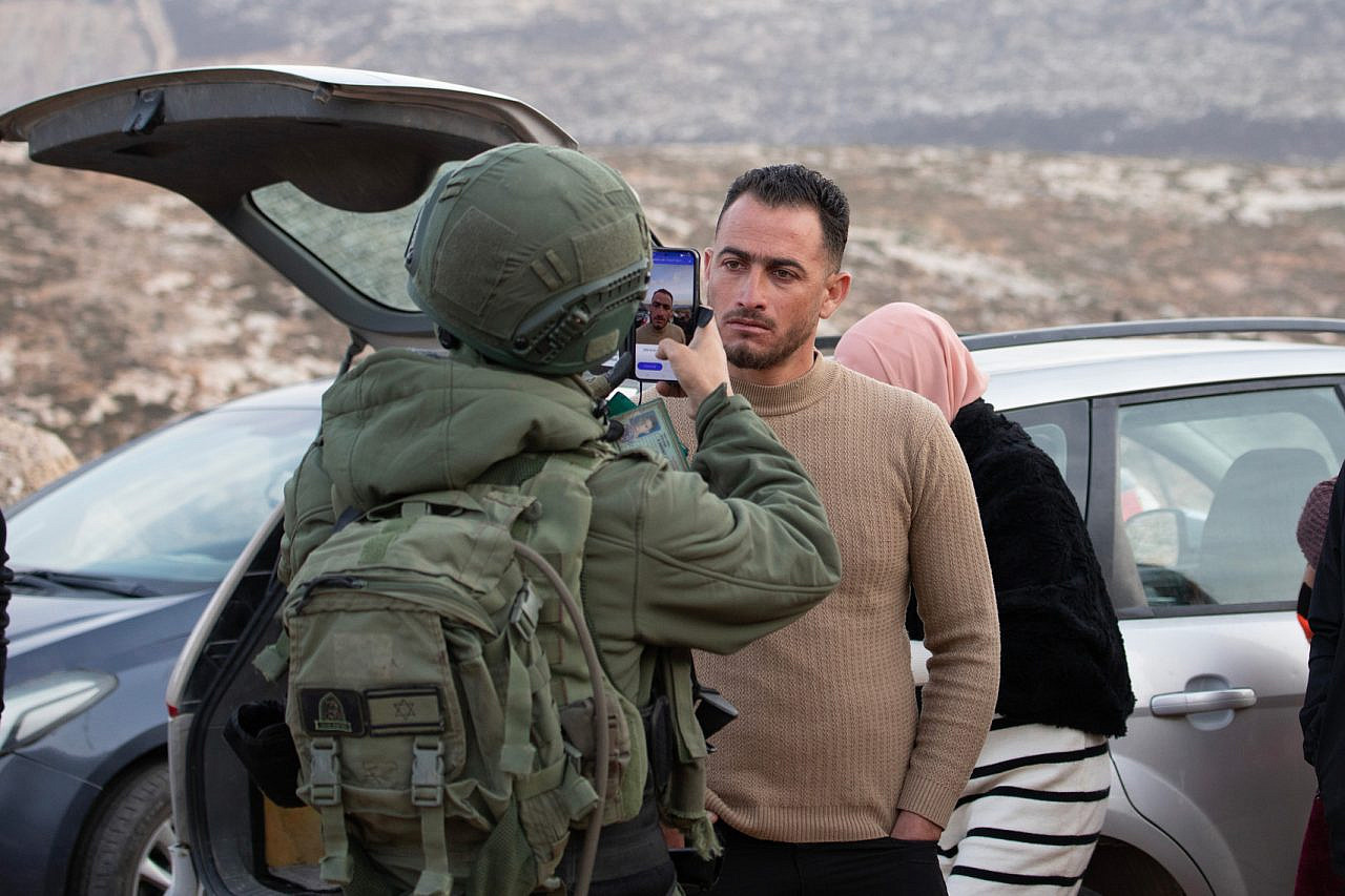 An Israeli soldier photographs a Palestinian man using an AI facial recognition tool during a raid in Wadi Qutyna, Al-Mughayer, occupied West Bank, January 17, 2025. (Avishay Mohar/Activestills)