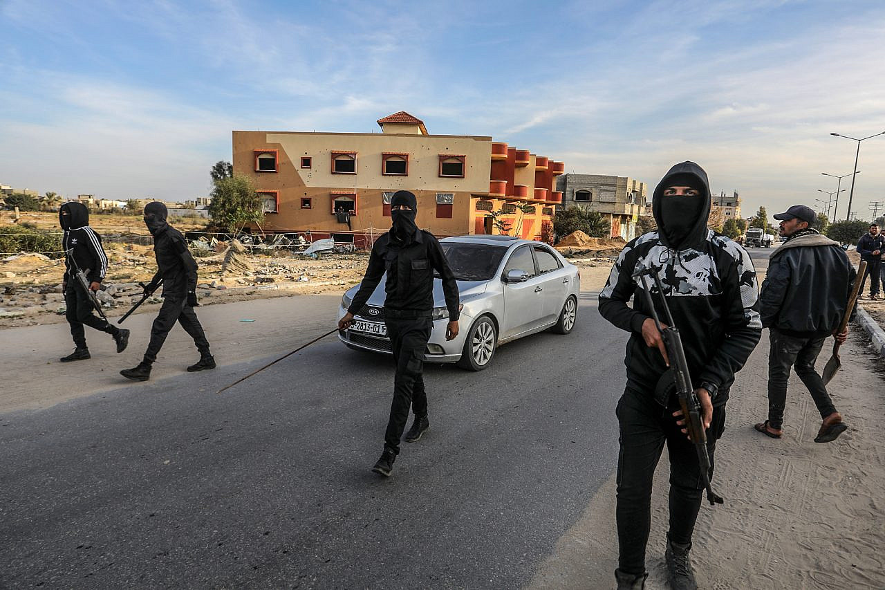 Armed and masked Palestinians secure trucks loaded with humanitarian aid entering Gaza through the Israeli Kerem Shalom Crossing, on Salah al-Din Road east of Khan Younis, in the southern Gaza Strip, Jan. 19, 2025. (Abed Rahim Khatib/Flash90)