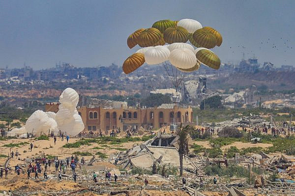Palestinians rush to the site where parachuted aid packages land, in the Nuseirat area of the central Gaza Strip, August 8, 2025. (Ali Hassan/Flash90)