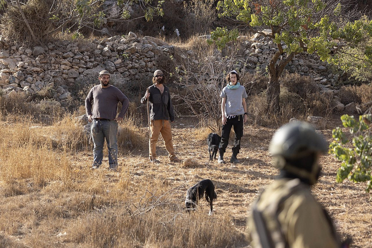 Israeli settlers from an outpost near the village of Sa'ir approach Palestinian farmers who have been harvesting olives, in the occupied West Bank, October 23, 2025. (Oren Ziv)
