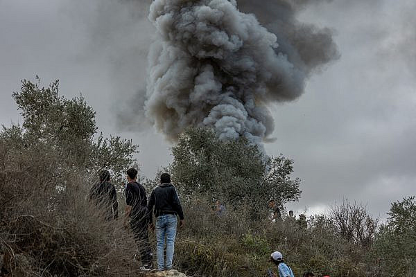 Palestinians watch smoke rising after a vehicle is set on fire by Israeli settlers during an attack on the first day of the olive harvest in the West Bank village of Beita, October 10 2025. (Avishay Mohar/Activestills)