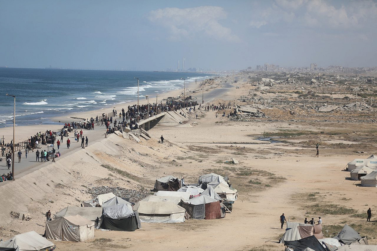 Palestinian families pass by tents as they return along Rashid Road from the southern parts of the Gaza Strip to the north, October 10, 2025. (Yousef Zaanoun/ActiveStills)