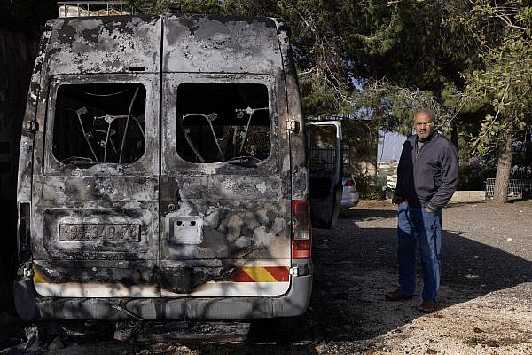 Ahmad Mousa Al-Mash’ala next to a van torched by Israeli settlers during an arson attack in the West Bank village of Jaba, November 18, 2025. (Oren Ziv)