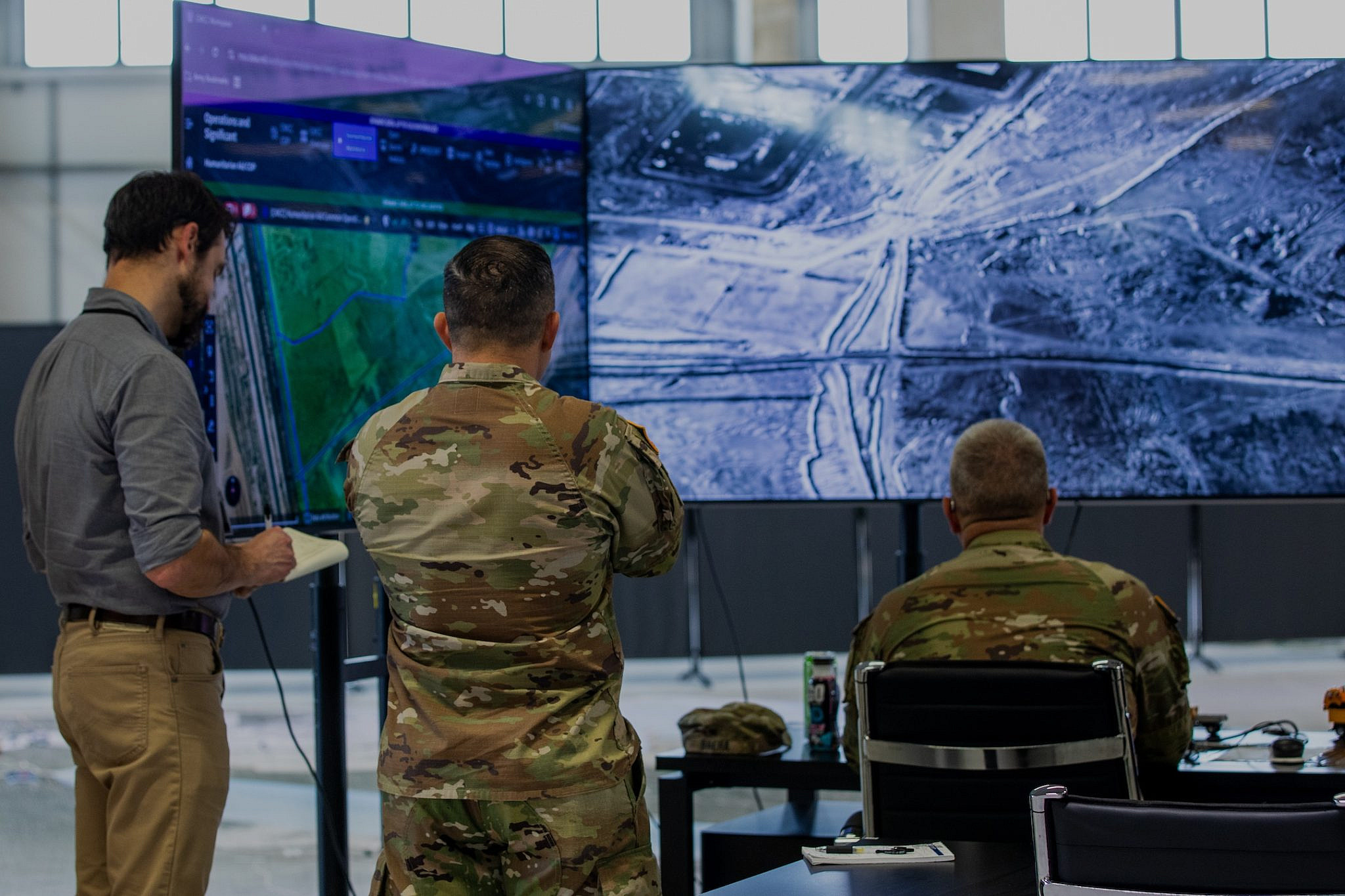 U.S. Army personnel and a representative of a Non-Government Organization stand in front of a monitor running Palantir software, at the Civil-Military Coordination Center in Kiryat Gat, southern Israel, November 11, 2025. (U.S. Army photo by Spc. Kathryn Skonning/Wikicommons)
