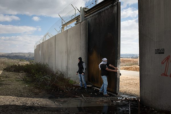 Palestinian youth open a gate of the separation wall during a demonstration marking 12 years of the struggle against the Israeli occupation, in the West Bank village of Bil'in, February 17, 2017. (Oren Ziv)