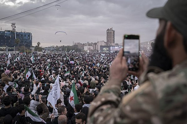 A member of the Syrian security forces films the celebrations in Umayyad Square for the first anniversary of Assad's fall, in Damascus, Syria. (Santiago Montag)