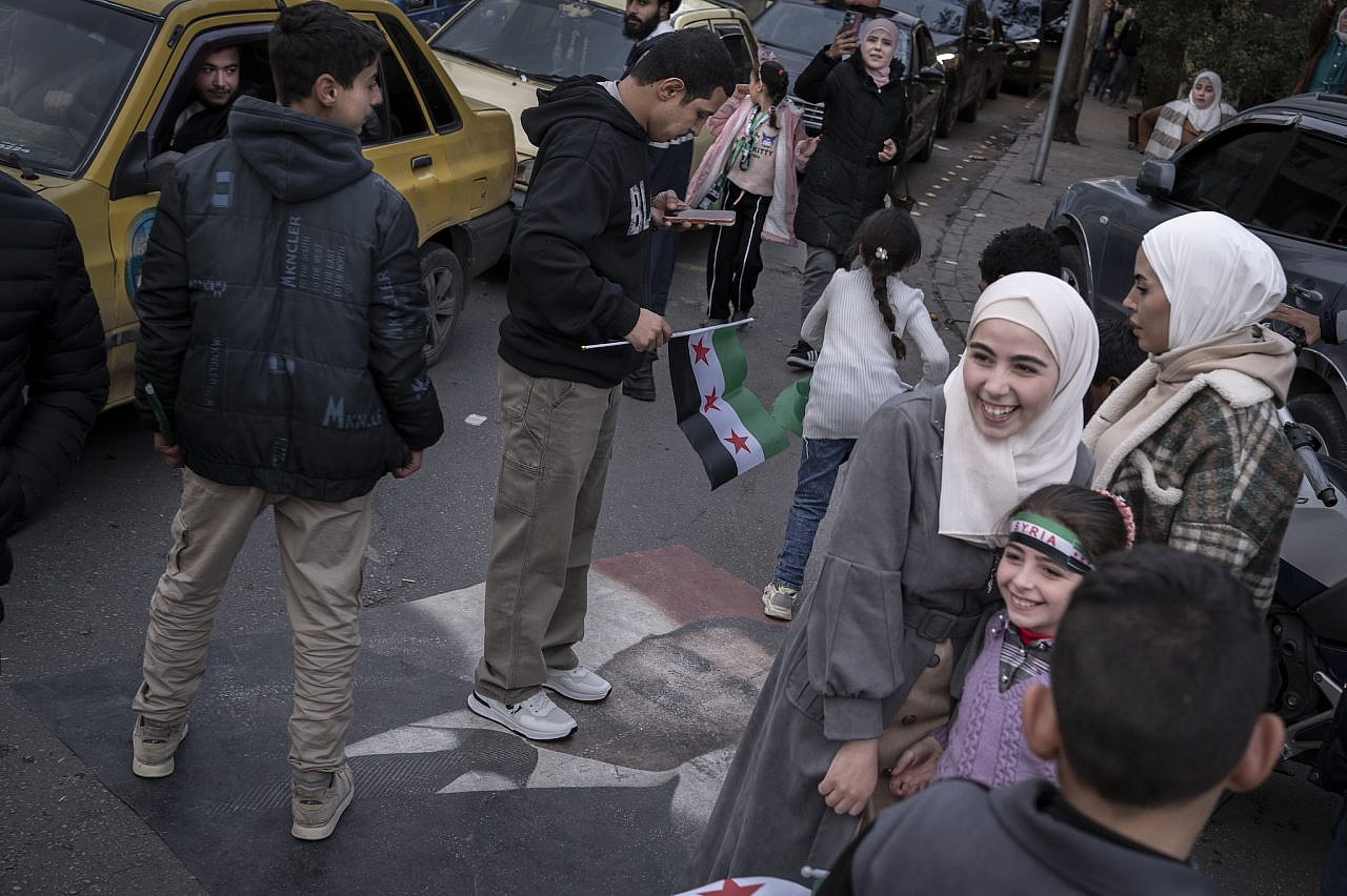 A portrait of Bashar Al-Assad placed on the sidewalk to be trampled by passersby heading towards Umayyad Square to celebrate the anniversary of the regime's downfall, in Damascus, Syria. (Santiago Montag)