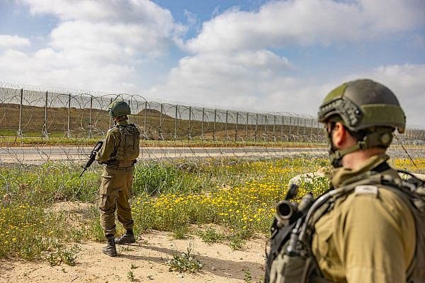 Israeli soldiers stand guard on the Israeli side of the fence surrounding the Gaza Strip, March 18, 2025. (Chaim Goldberg/Flash90)