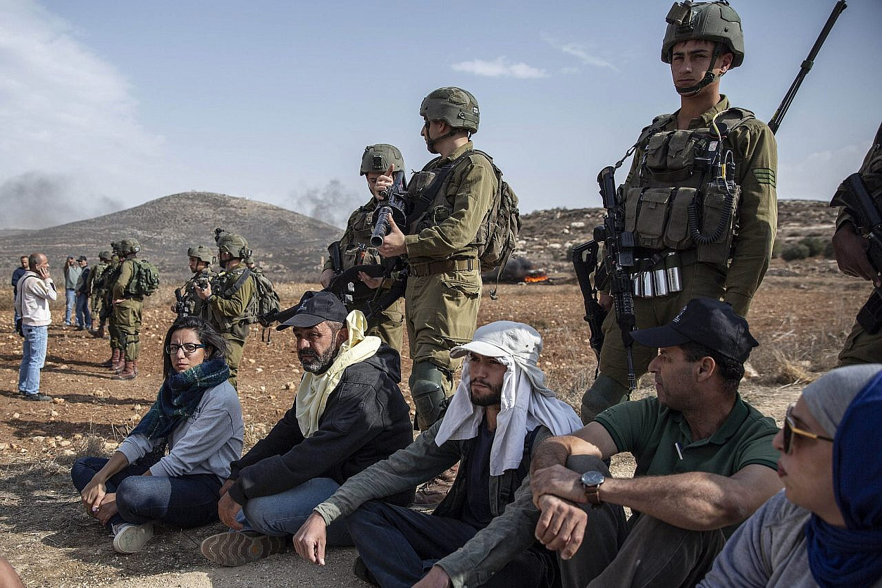 Israeli soldiers block Palestinian farmers and activists from the Faz3a campaign and other groups from reaching their olive trees after a settler attack near an Israeli outpost, Turmus Ayya, occupied West Bank, October 25, 2022. (Anne Paq/Activestills)