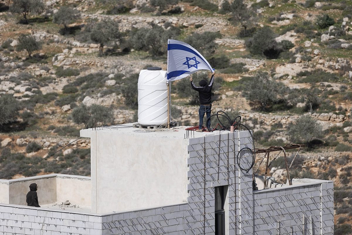 Israeli settlers fly an Israeli flag on the house of Ahed Khatib, inside Area B near Aqarba, in the West Bank, February 2026. (Oren Ziv) Israeli settlers fly an Israeli flag on the house of Ahed Khatib, inside Area B near Aqarba, in the West Bank, February 2026. (Oren Ziv)