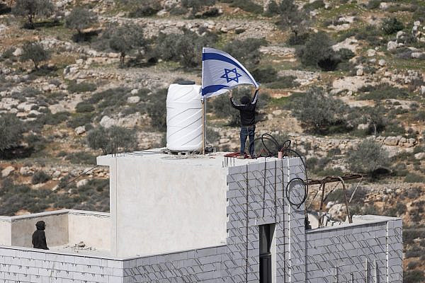 Israeli settlers fly an Israeli flag on the house of Ahed Khatib, inside Area B near Aqarba, in the West Bank, February 2026. (Oren Ziv)