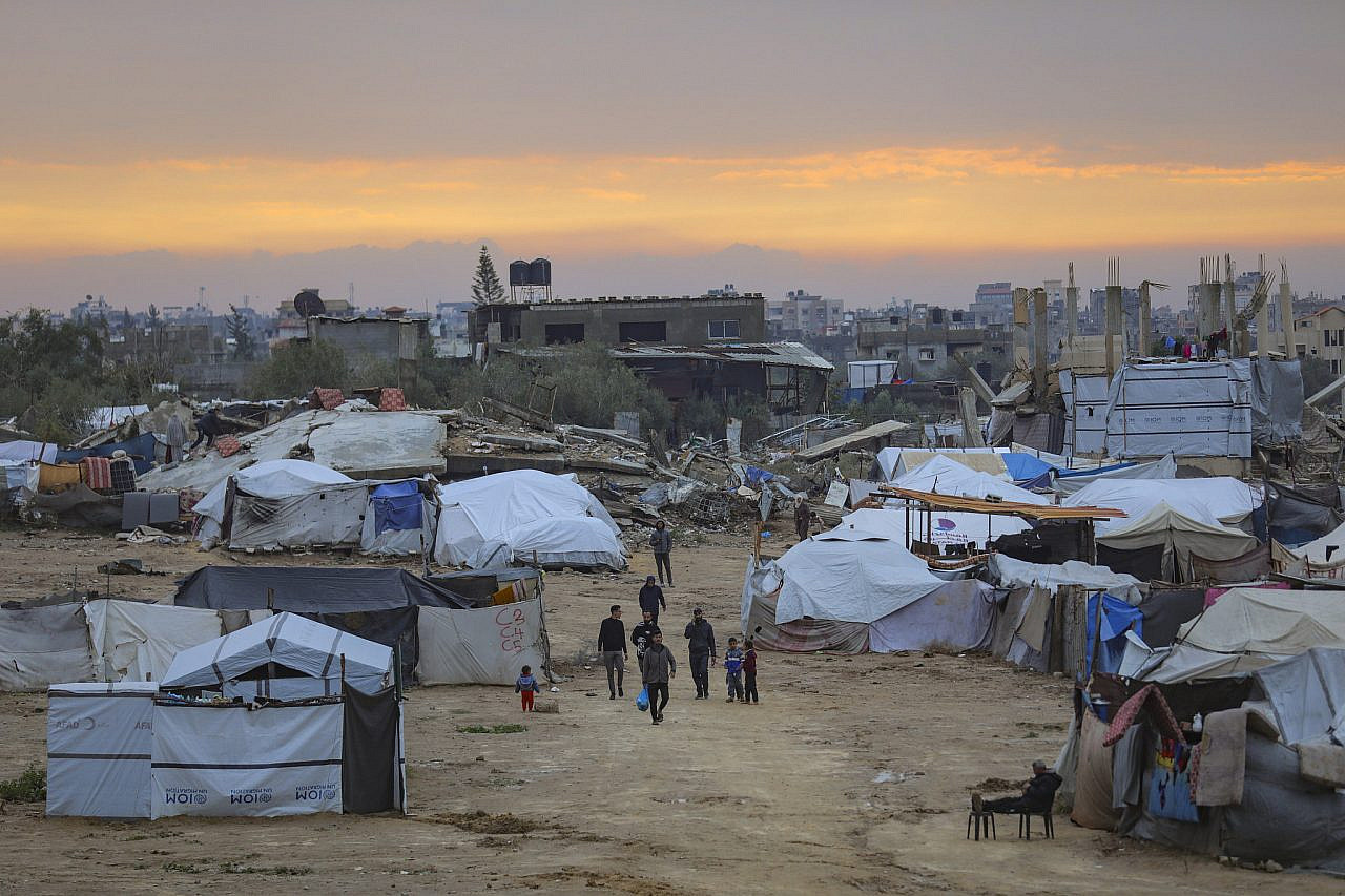 Displaced Palestinians are seen near their tents at sunset in Deir Al-Balah, in the central Gaza Strip, December 12, 2025. (Ali Hassan/Flash90)