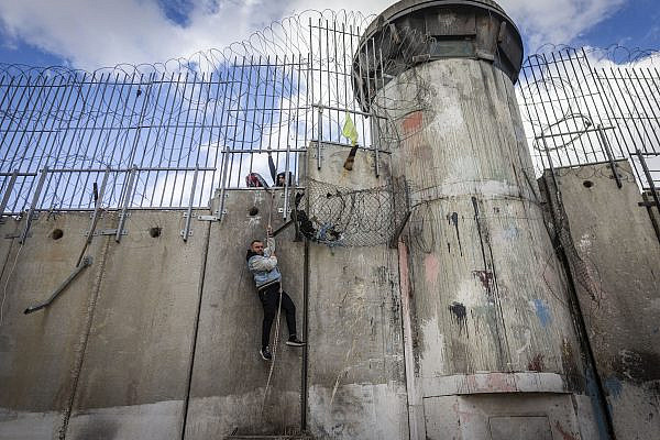 Palestinians use a rope to climb over the separation barrier from the al-Ram village into East Jerusalem, January 12, 2026. (Chaim Goldberg/Flash90)