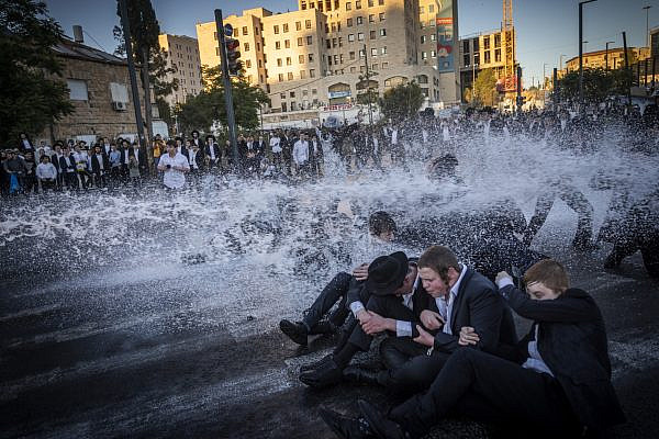 Ultra-Orthodox men being sprayed with a police water cannon during a protest against the imprisonment of yeshiva students who failed to comply with army draft orders, in Jerusalem, June 1, 2026. (Yonatan Sindel/Flash90)