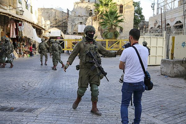 An Israeli soldier confronts a photographer documenting a raid on the Old City of Hebron, the occupied West Bank, October 4, 2025. (Mosab Shawer/Activestills)