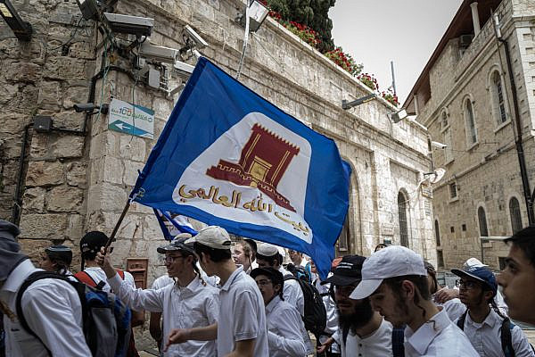A participant in the Jerusalem Day Flag March carries a flag bearing the image of the Temple Mount, in Jerusalem's Old City, May 14, 2026. (Faiz Abu Rmeleh/Activestills)