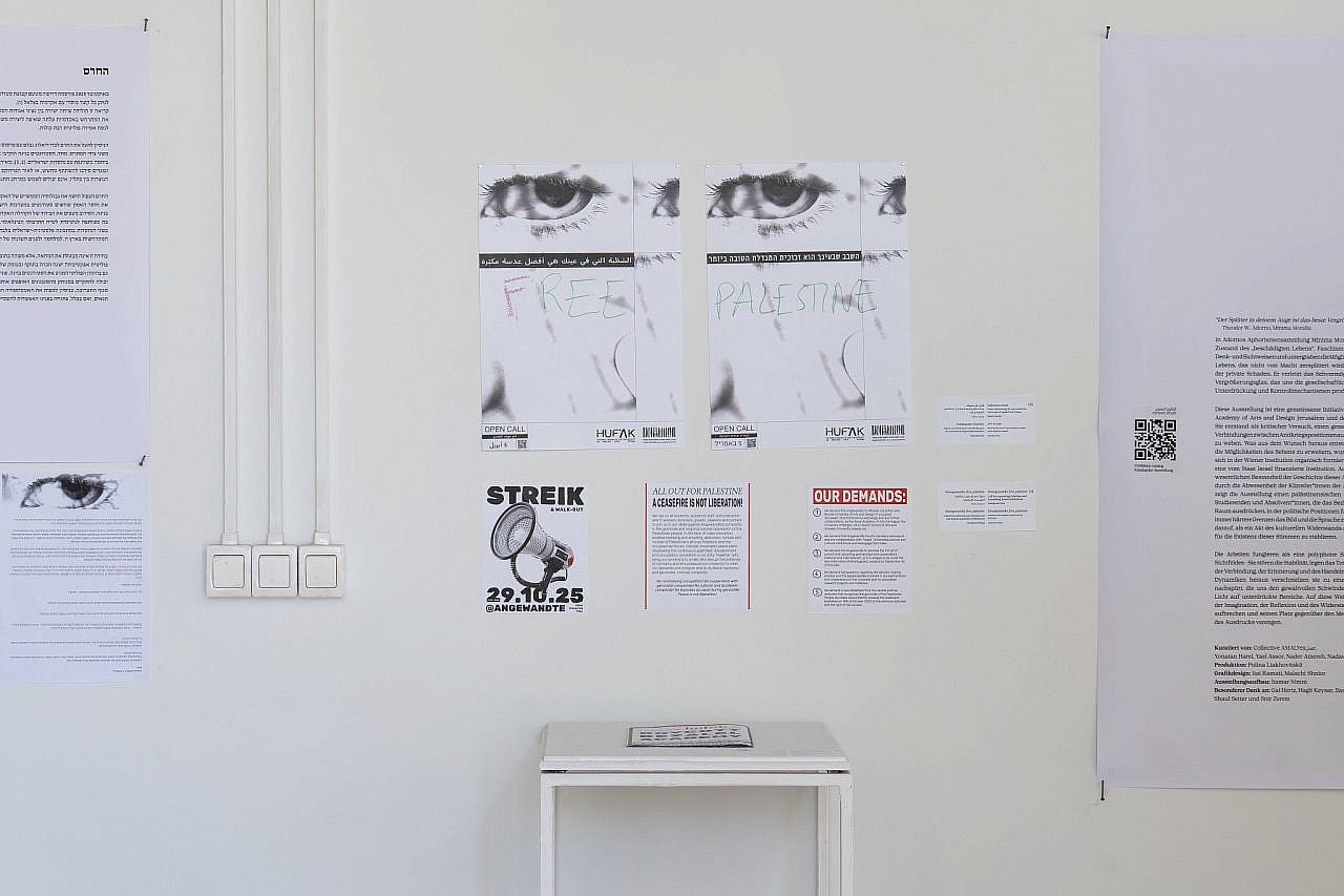 Reproductions of the defaced original open call posters, on which students at the University of Applied Arts Vienna graffitied "Free Palestine," displayed alongside a pamphlet outlining their demand that the university cut ties with Bezalel, as exhibited in Bezalel Academy of Arts and Design, Jerusalem, June 22, 2026. (Hadas Hay)