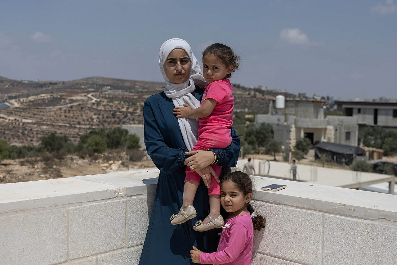 Ruqaya Hassan and her daughters overlooking their besieged house in the village of Qusra, occupied West Bank, August 14, 2026. (Oren Ziv)
